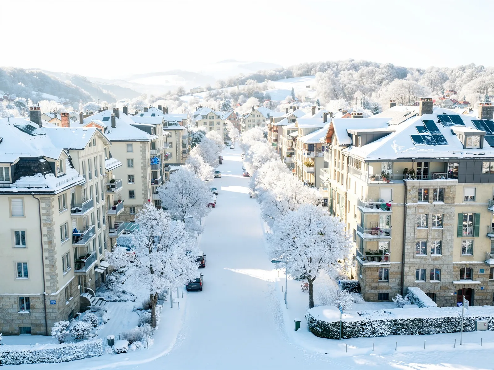 Solider Schweizer Wohnbestand an einer baumbestandenen Strasse mit Photovoltaik auf den Dächern, im Winter