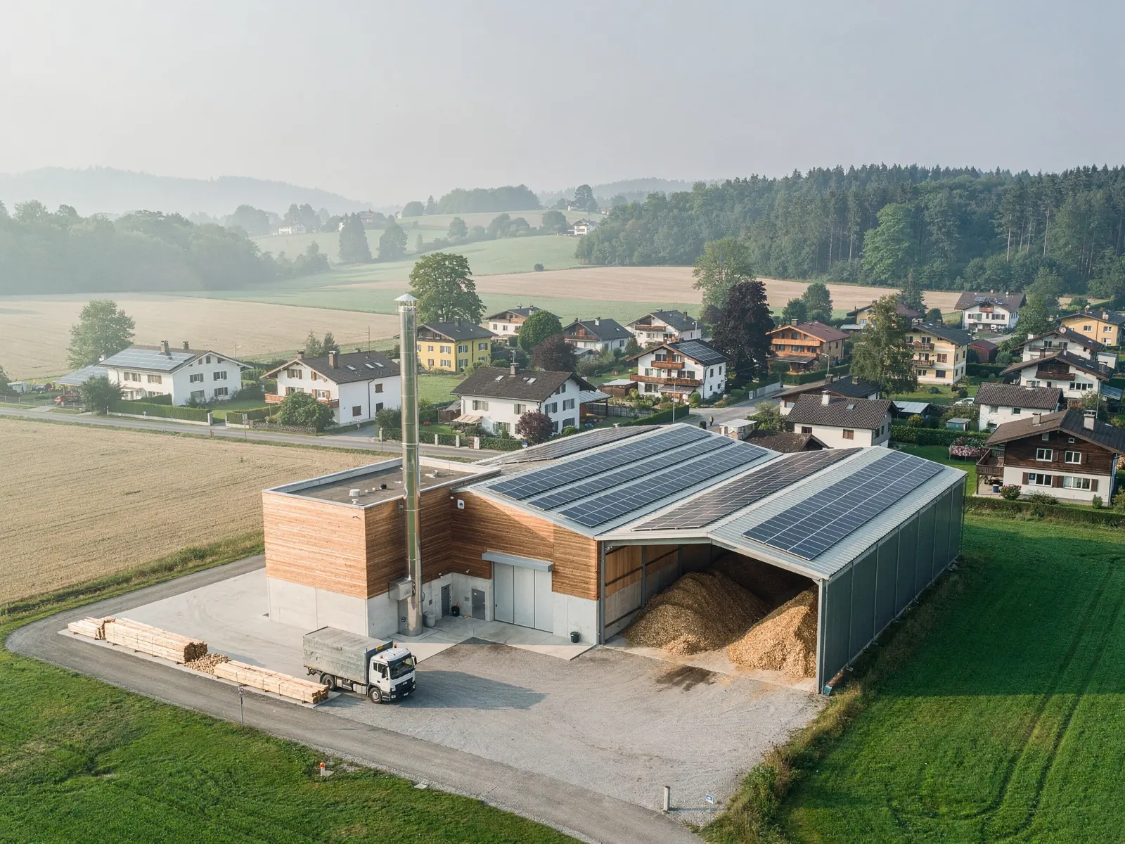 Holzheizzentrale am Rand eines Schweizer Dorfes mit Schnitzellager, Anlieferung und Photovoltaik auf dem Dach